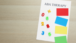 Phrase ABA Therapy and different colors with numbers on white wooden table, top view. Space for text